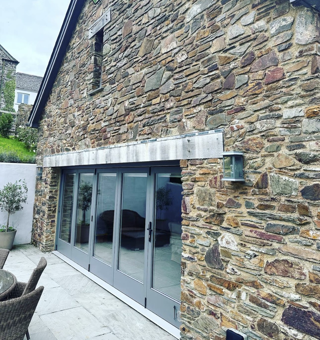 Stone barn with grey glazed doors viewed from the side