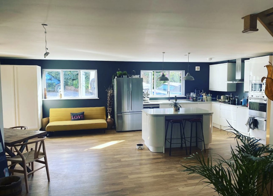 Open-plan kitchen with navy walls and white cabinetry