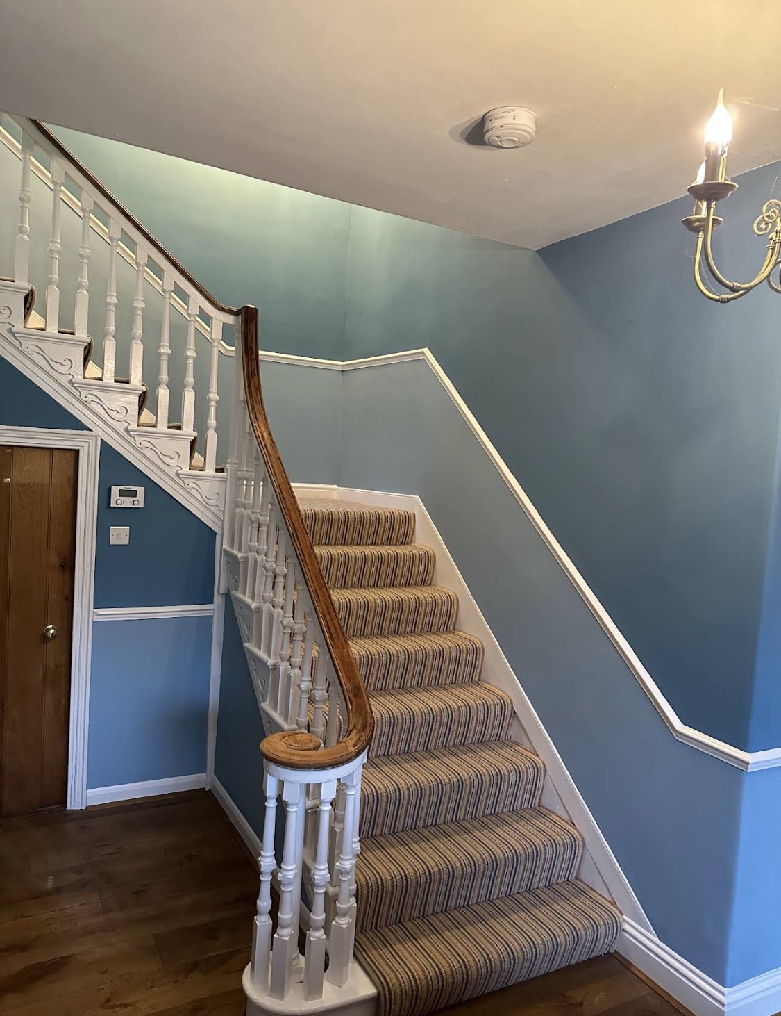 Sweeping staircase with blue walls and striped runner