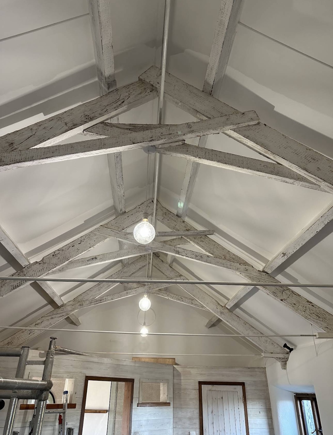 Vaulted white ceiling and beams — scaffolding, work in progress