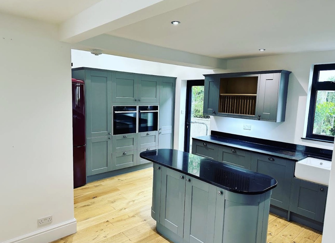 Blue-grey painted kitchen with black worktops and island