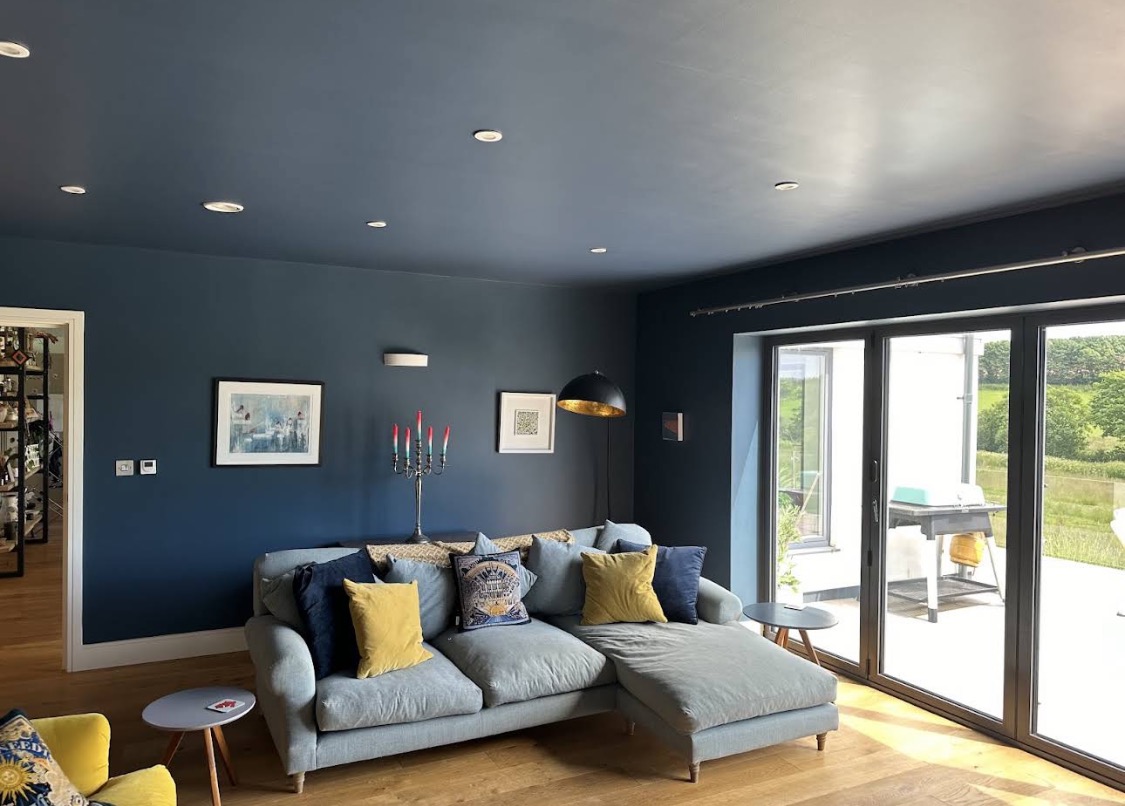 Deep-blue living room with pale sofa and mustard cushions