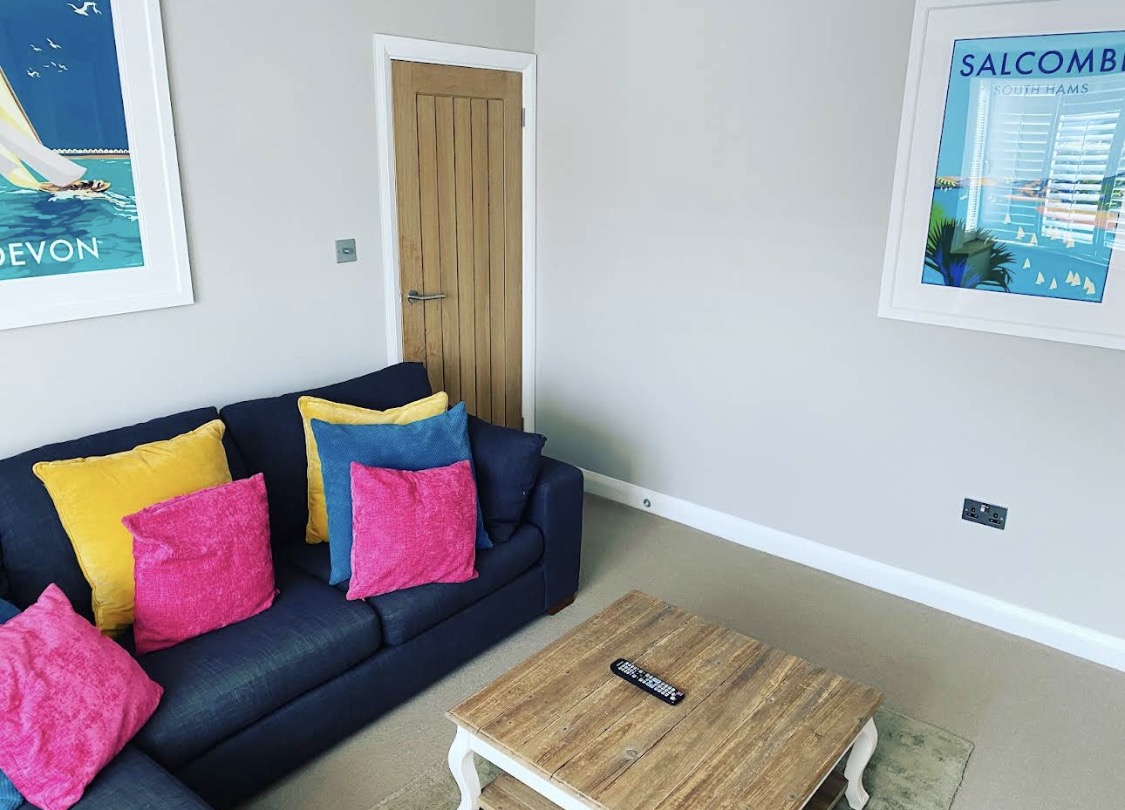 Bright grey living room with navy sofa and colourful cushions