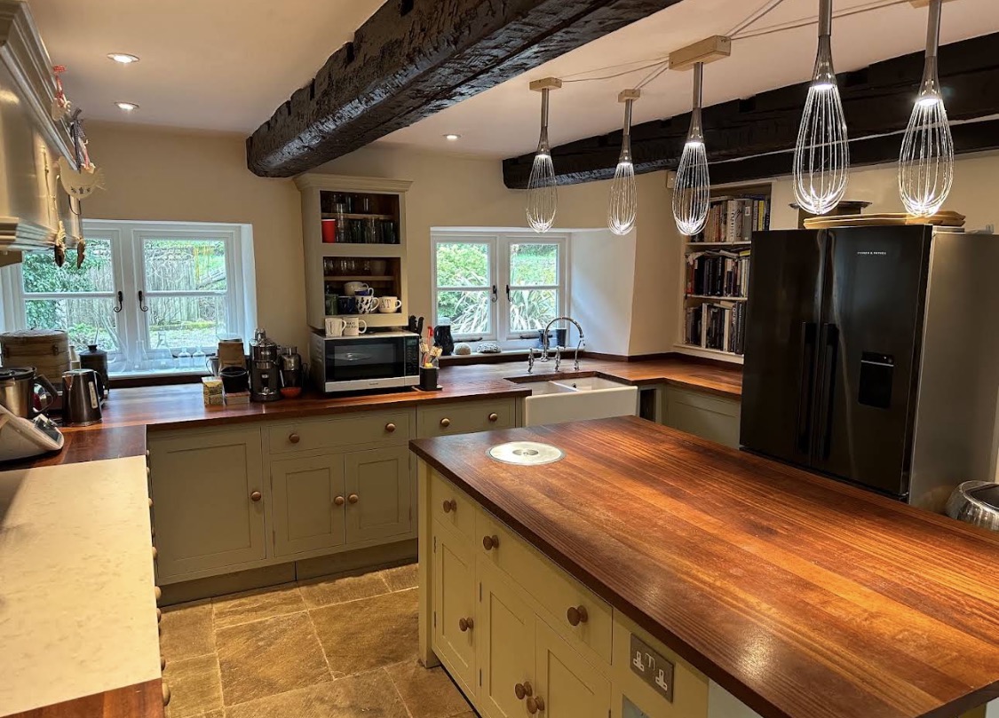 Olive-grey painted kitchen with wooden worktops and beams