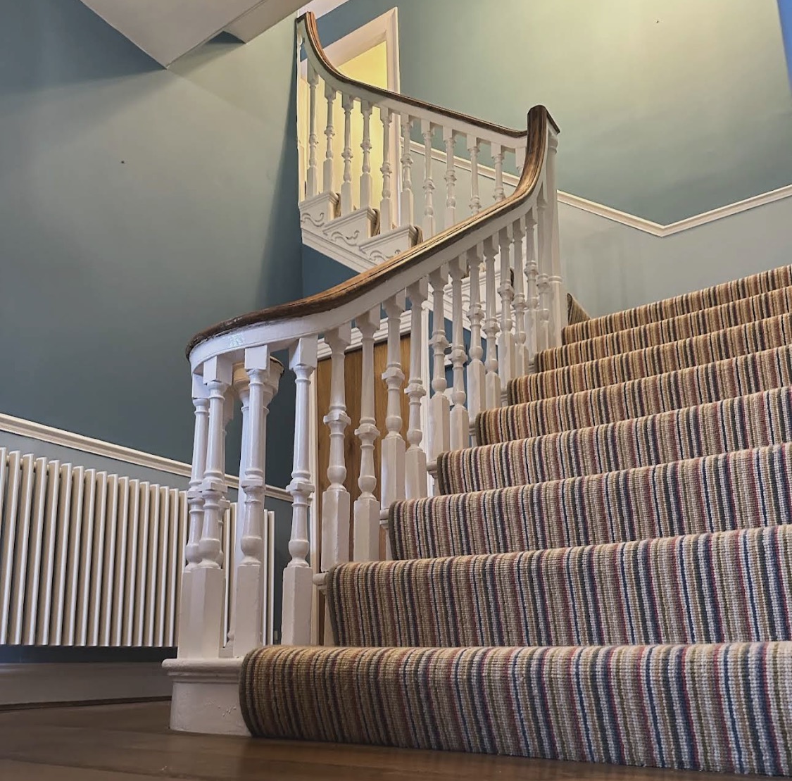 Curving white balustrade and wooden handrail against blue walls