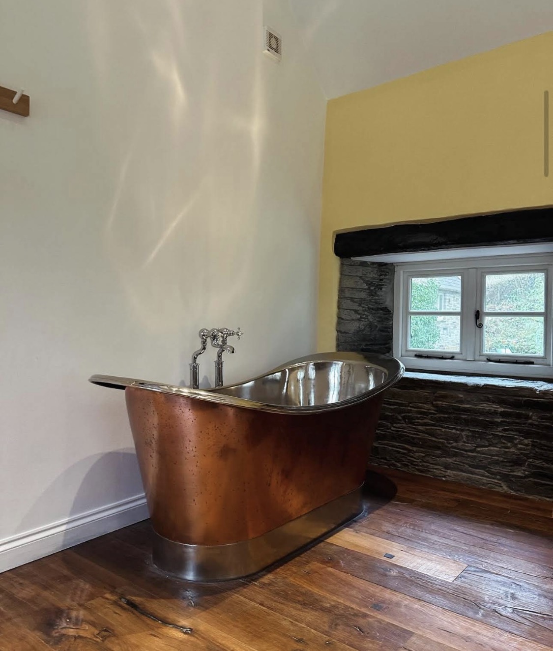 Copper bath beside a yellow accent wall
