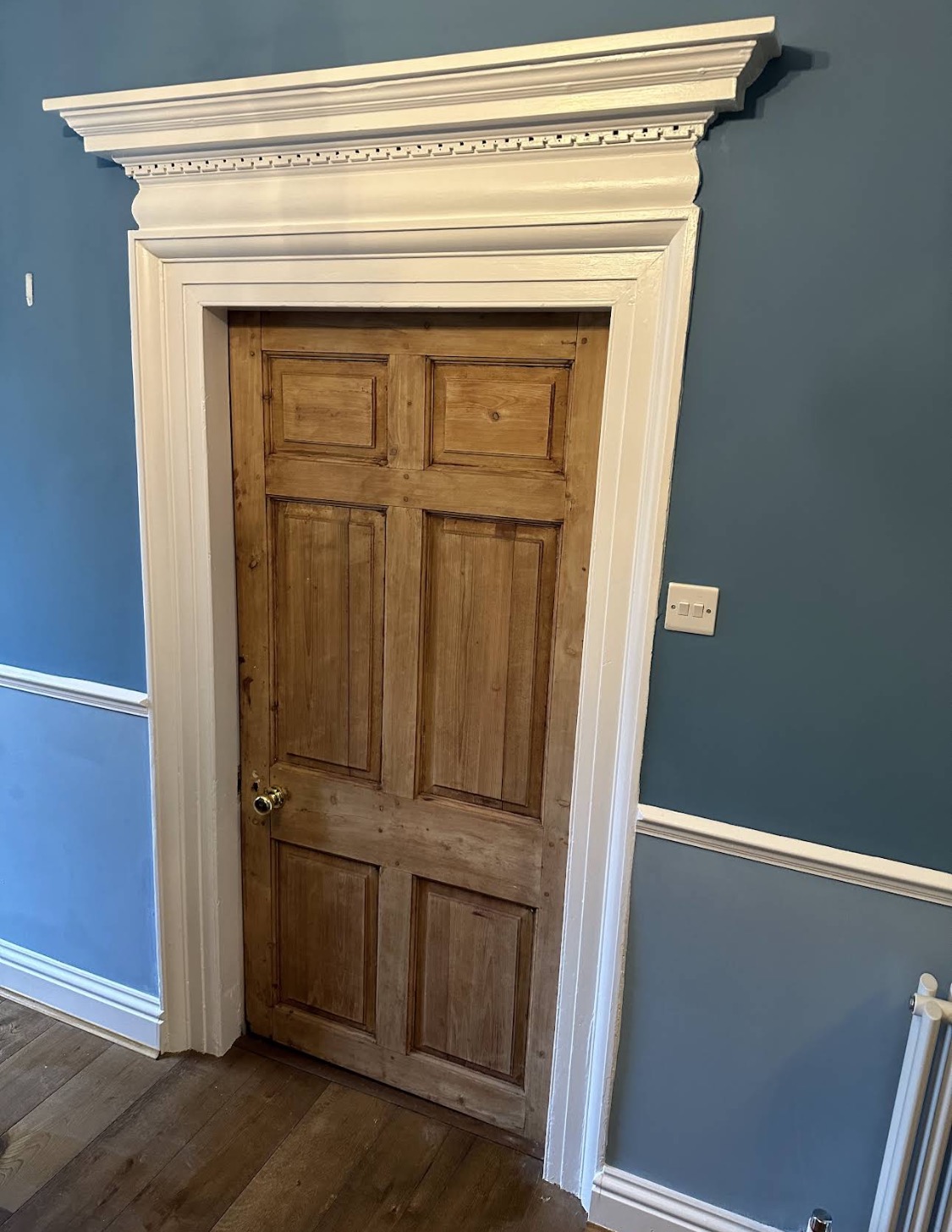 Ornate white doorframe and wooden door against blue walls