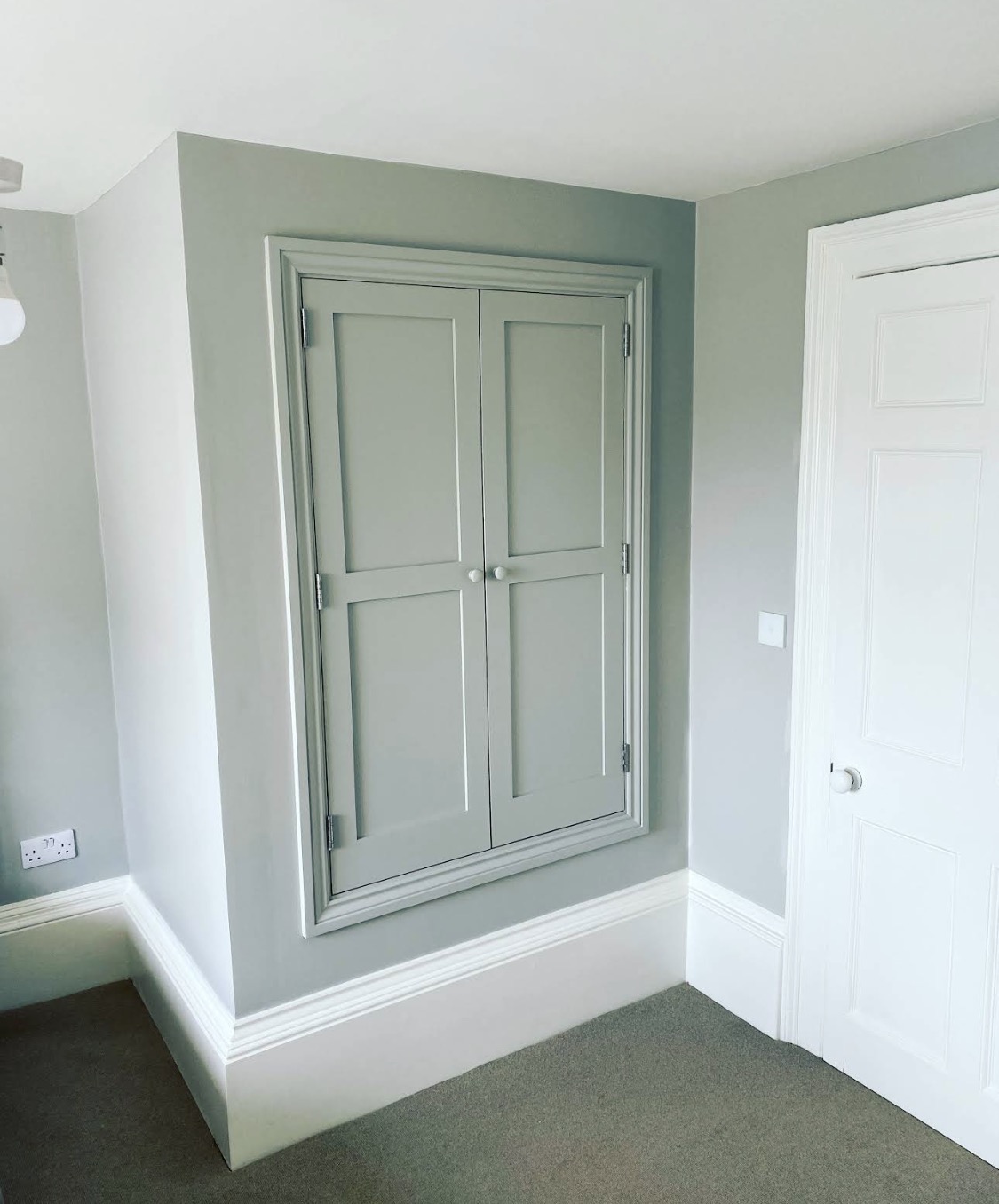Sage painted built-in cupboard with white woodwork